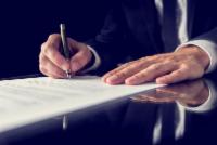 photo: man signing document with pen