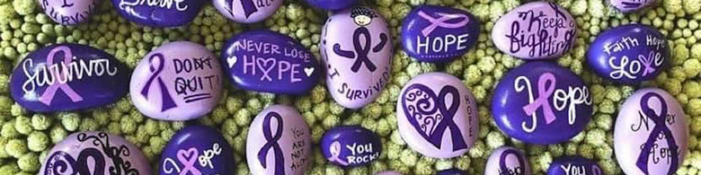 Small painted rocks with painted purple ribbon symbols.